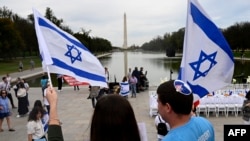 People wave Flags of Israel as a “Shabbat Dinner” table is prepared with 200 empty seats representing the Israeli hostages and missing people, at the Lincoln Memorial in Washington, DC, on Oct. 27, 2023.