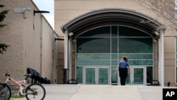 FILE - In this April 17, 2019, file photo, a police officer walks to the front doors of Columbine High School in Littleton, Colo., where two students killed 12 classmates and a teacher in 1999.
