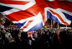 FILE - A man waves a British flag on Brexit day in London, Jan. 31, 2020.