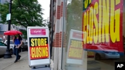 FILE - A passer-by is shown near a storefront with closing signs in Boston, Sept. 2, 2020. The U.S. unemployment rate dropped to 7.9% in September, but hiring is slowing and many Americans have given up looking for work, federal officials say.