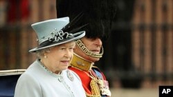Britain's Queen Elizabeth and Prince Philip sit in a horse drawn carriage as they make their way from Buckingham Palace to attend the Trooping the Colour ceremony in central London, June 11, 2011