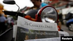 រូប​ឯកសារ៖ ស្ត្រីម្នាក់​​ទិញ​កាសែត​ The Cambodia Daily ដែល​បោះពុម្ព​ផ្សាយ​លេខ​ចុងក្រោយ​ នៅ​តូប​លក់​កាសែត​មួយ​ក្នុង​រាជធានី​ភ្នំពេញ​ ប្រទេស​កម្ពុជា​ ថ្ងៃទី៤​ ខែ​កញ្ញា​ ឆ្នាំ២០១៧។​ (Reuters / Samrang Pring)