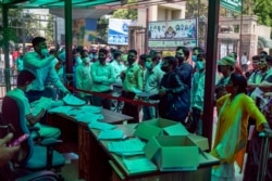 A hospital staff tries to calm down an impatient crowd during the registration process for getting tested for COVID-19 at a government hospital in Noida, a suburb of New Delhi, India, April 13, 2021.