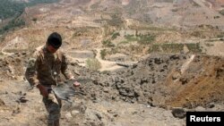 A Lebanese army member holds the remains of Israeli ammunition as he stands near the damage in the aftermath of Israeli air strikes near the border with Israel, Lebanon on Aug. 5, 2021.