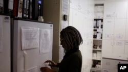 FILE - Pharmacist Mary Chindanyika looks at documents on a fridge containing a trial vaccine against HIV on the outskirts of Cape Town, South Africa, Nov. 30, 2016. 
