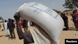 A worker of World Food Programme (WFP) carries a bag of relief grains to be distributed to Sudanese refugees who have fled the violence in their country, near the border between Sudan and Chad, in Koufroun, Chad April 28, 2023.