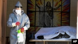 A health worker disinfects the area next to a coffin with the remains of a recently deceased resident of the San Jose nursing home in Cochabamba, Bolivia, July 16, 2020.