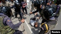 បុរស​ម្នាក់​ព្យាយាម​ការពារ​ខ្លួន​ខណៈ​ដែល​ក្រុម​ប៉ូលិស​ចោម​រោម​វាយ​លោក​ក្នុង​អំឡុង​ពេល​​បាតុកម្ម​មួយ​ដើម្បី​ប្រារព្ធ​​ទិវា​ពលកម្ម​អន្តរជាតិ​កាល​ពី​ថ្ងៃ​ទី​១ ខែ​ឧសភា ឆ្នាំ​២០១៤។