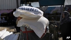 FILE - Palestinians receive food aid at a U.N. warehouse in the Shati refugee camp, Gaza City, Jan. 14, 2018.
