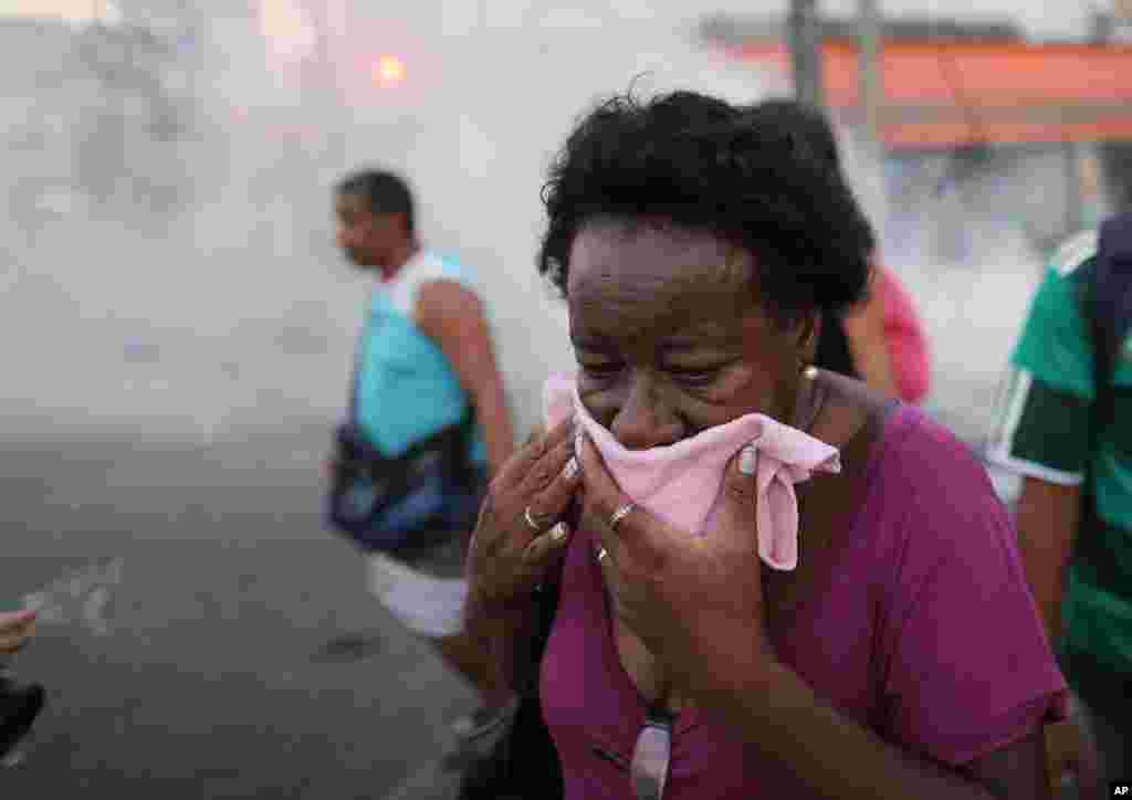 A woman covers her face to protect herself against tear gas used by police during a protest against a bus fare increase in Rio de Janeiro, Feb. 6, 2014.