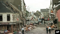 FILE - Royal Ulster Constabulary Police officers stand on Market Street, the scene of a car bombing in the centre of Omagh, Co Tyrone, 72 miles west of Belfast, Northern Ireland, on Aug. 15, 1998. It has been 25 years since the striking of the Good Friday Agreement, the landmark peace accord that ended three decades of violence in Northern Ireland, a period known as “the Troubles.”