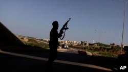 FILE - A Libyan rebel mans a check point on the outskirts of Benghazi, Libya, March 30, 2011. Fighting was continuing Saturday for control of the country's oil facilities around the city.