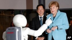 អធិការបតី​អាល្លឺម៉ង់ Angela Merkel ស្តាំ​ មើល​រូប៉ូត​របស់​ក្រុមហ៊ុន Honda Motor Co.’s នៅ​ឯ​សារៈមន្ទីរ​ជាតិ​​នៃ​វិទ្យាសាស្រ្ត​ថ្មី​ៗ​និង​ការ​ច្នៃ​ប្រឌិត​ Miraikan នៅ​ក្នុង​ដំណើរ​ទស្សនកិច្ច​របស់​លោក​ស្រី​ នៅ​ក្នុង​ទី​ក្រុង​តូក្យូ កាល​ពី​ថ្ងៃ​ច័ន្ទ​ ទី​៩ ខែ​មីនា​ ឆ្នាំ​២០១៥។