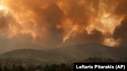 FILE - In this Friday, Aug. 6, 2021 file photo, smoke spreads over Parnitha mountain during a wildfire in the village of Ippokratios Politia, Greece, about 35 kilometres (21 miles), north of Athens. (AP Photo/Lefteris Pitarakis)