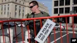 An armed U.S. Marshal lifts the security barricade around the federal courthouse where Libyan militant Ahmed Abu Khattala's hearing was held, in Washington, Oct. 20, 2014.