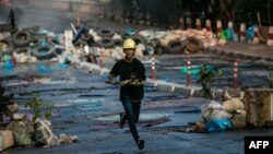 Seorang pengunjuk rasa berlari di sepanjang jalan sambil membawa pedang saat berlangsungnya penumpasan terhadap aksi protes menentang kudeta militer di Yangon, 16 Maret 2021. (Foto: STR / AFP)