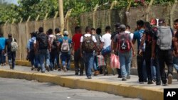 FILE - Central American migrants cross into Mexico from Guatemala, near Ciudad Hidalgo, Mexico, June 4, 2019. The migrants walked over the bridge and waited to register at a Mexican immigration office.
