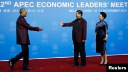 U.S. President Barack Obama (L) shakes hands with China's President Xi Jinping as Xi's wife, Peng Liyuan, looks on, during the APEC Welcome Banquet in Beijing, Nov. 10, 2014.