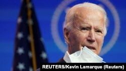 U.S. President-elect Joe Biden holds up a face mask as he speaks about the U.S. economy following a briefing with economic advisers in Wilmington, Delaware, U.S., November 16, 2020. REUTERS/Kevin Lamarque
