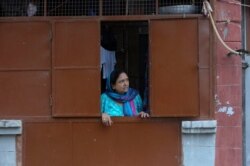 A Kashmiri Hindu woman looks from inside her residence at the Jagti migrant camp in Jammu, India, Aug. 23, 2019. Tens of thousands of Kashmiri Hindus fled the restive region nearly 30 years ago.