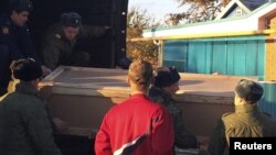 Russian servicemen unload a coffin containing the body of Vadim Kostenko, a member of the Russian air force's support staff in Syria, from a truck near his family's house in Grechanaya Balka, Russia, Oct. 27, 2015.