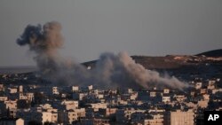 FILE - Thick smoke from an airstrike by the US-led coalition rises in Kobani, Syria, as seen from a hilltop on the outskirts of Suruc, at the Turkey-Syria border, Oct. 21, 2014. 