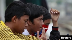 Seorang remaja pria mengisap rokok di pinggir rel kereta api di Jakarta. (Reuters/Beawiharta)