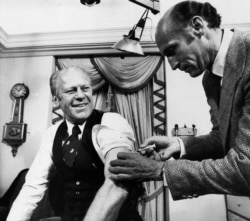 FILE - U.S. President Gerald Ford rolls up his sleeve and receives a swine flu shot from White House physician Dr. William Lukash, Oct. 14, 1976.
