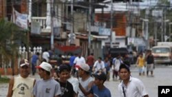 People walk on a street flooded in Rio Chico, central Venezuela, Saturday, Dec. 4, 2010.