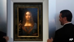 Security guards open a door to reveal "Salvator Mundi" by Leonardo da Vinci during a news conference at Christie's in New York, Tuesday, Oct. 10, 2017. The piece, which was painted around 1500, is one of fewer than twenty da Vinci paintings known to exist. After public exhibitions around the world, the auction is scheduled to take place on Nov. 15, 2017. (AP Photo/Seth Wenig)