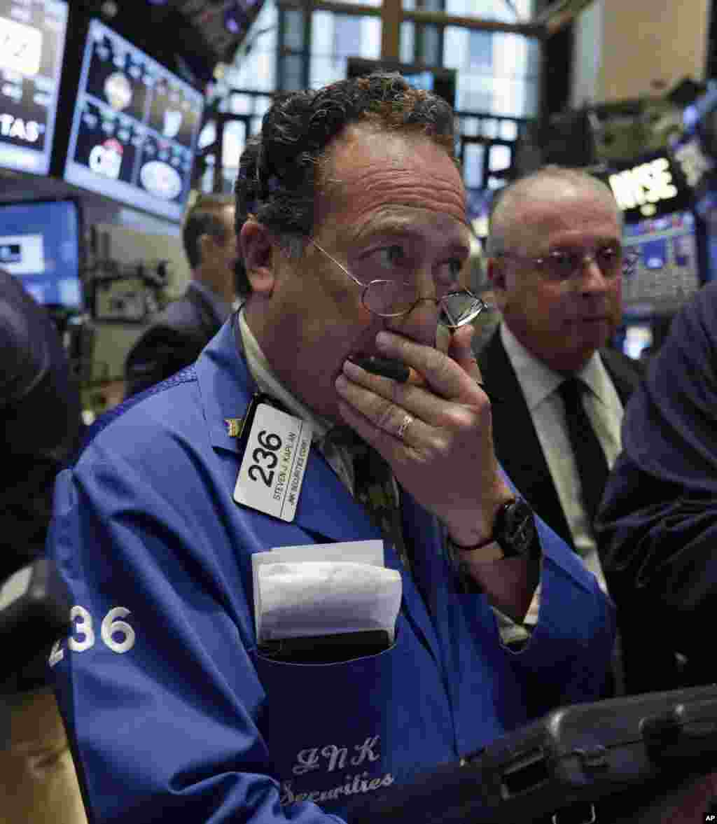 Worries about Russian troops amassing near the Ukrainian border are pushing stocks slightly lower. Trader Steven Kaplan, left, works on the floor of the New York Stock Exchange, New York, NY, Aug. 6, 2014.