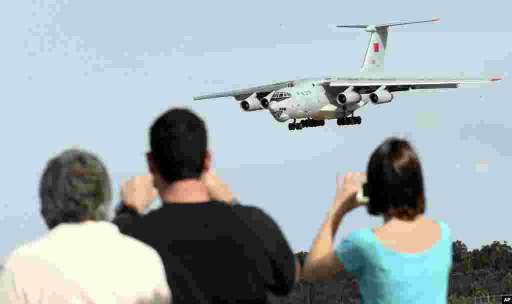 Spectators take photos of a Chinese Ilyushin IL-76 aircraft as it comes in for a landing at Perth International Airport after returning from the ongoing search operations for missing Malaysia Airlines Flight 370, Perth, Australia, April 10, 2014.