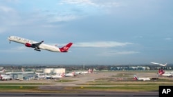 Virgin Atlantic flight VS3, front, and British Airways flight BA001 perform a synchronised departure on parallel runways at London Heathrow Airport, Monday, Nov. 8, 2021 heading for New York's JFK airport. (Anthony Upton/PA via AP)