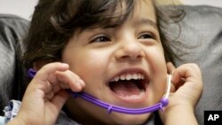 FILE - Three-year-old Amina of Iraq laughs during a hearing test. The WHO reports 360 million people around the globe suffer from disabling hearing loss and that nearly 32 million are children.