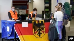 Foreign tourists wait to be checked by German Embassy staff at Christchurch Airport terminal as they prepare to check in for a charter flight back to Germany via Vancouver from Christchurch, New Zealand, Monday, April 6, 2020.