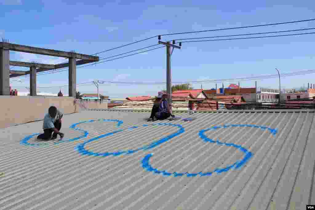 ពលរដ្ឋ​នៅ​ភូមិ​ត្រពាំង​ល្វា​ក្នុង​សហគមន៍​&laquo;SOS&raquo; នាំ​គ្នា​សរសេរ​អក្សរ​ថា &laquo;SOS&raquo; លើ​ដំបូល​ផ្ទះ​របស់​ពួក​គេ ដើម្បី​ឲ្យ​មាន​ការ​ចាប់​អារម្មណ៍​ពី​លោក ហ៊ុន សែន ពេល​លោក​ត្រលប់​មក​ពី​កិច្ចប្រជុំ​កំពូល​អាស៊ាន នៅ​ថ្ងៃ​ទី​១៣​ ខែ​វិច្ឋិកា ឆ្នាំ​២០១៤។ (នូវ ពៅលក្ខិណា VOA)