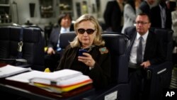 FILE - Then-secretary of state Hillary Clinton checks her BlackBerry from a desk inside a C-17 military plane upon her departure from Malta, in the Mediterranean Sea, bound for Tripoli, Libya, Oct. 18, 2011.