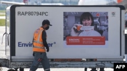 Seorang pekerja terlihat di samping kontainer berisi vaksin CoronaVac yang diturunkan dari pesawat kargo, setibanya di Bandara Internasional Guarulhos di Guarulhos, negara bagian Sao Paulo, Brazil, 18 Desember 2020. (Foto: dok).