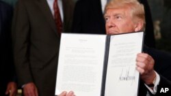 FILE - President Donald Trump holds up a signed memorandum calling for a trade investigation of China, Aug. 14, 2017, in the Diplomatic Reception Room of the White House in Washington.