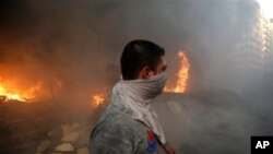 A Hezbollah civil defense worker walks past a burned car at a car bomb in the southern suburb of Beirut, Lebanon, Thursday, Aug. 15, 2013. 