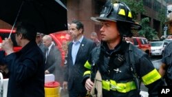 Gubernur New York Andrew Cuomo (tengah) dan petugas gawat darurat berada di lokasi kecelakaan helikopter di atas sebuah gedung di pusat Manhattan, 10 Juni 2019, di New York.
