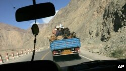 FILE - Ethnic Uighurs and camels ride together in the back of a truck along the Karakoram Highway from Kashgar towards Karakul lake in Chinas Xinjiang autonomous region, May 22. 2006. 