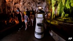 Persephone guides the visitors inside Alistrati cave, about 135 kilometers northeast of Thessaloniki, Greece, Monday, Aug. 2, 2021. (AP Photo/Giannis Papanikos)