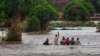In this image made from video, people walk on a road swept by flooding waters in Chikwawa, Malawi, Jan. 25, 2022.
