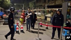 FILE - Residents walk past a security checkpoint at the close of a open-air market in Kashgar in western China's Xinjiang region, Nov. 4, 2017. Authorities are using detentions in political indoctrination centers and surveillance in efforts to control the Xinjiang region and its Uighurs, a Turkic-speaking Muslim minority Beijing fears could be influenced by extremism. 