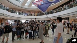 Para pengunjuk rasa menunjukkan Paspor Nasional Inggris (Luar Negeri) dan bendera Hong Kong di sebuah pusat perbelanjaan dalam unjuk rasa memprotes Undang-Undang Keamanan China, di Hong Kong, 29 Mei 2020.