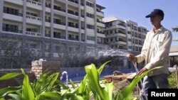 FILE - A worker waters plants in front of an eight-story building in the Lao capital of Vientiane on December 1, 2000. Laos is one of 47 nations on the list of United Nations’ Least Developed Countries. It is hoping to move up from the list in the coming year.
