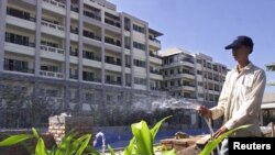 រូបឯកសារ៖ បុគ្គលិក​ម្នាក់​ស្រោច​ដំណាំ​នៅ​មុខ​អគារ​ខុនដូរ​កម្ពស់​ ៨ ជាន់​នៅ​ក្នុង​ទីក្រុង​វៀងច័ន្ទ ប្រទេស​ឡាវ ថ្ងៃទី១ ខែធ្នូ ឆ្នាំ២០០០។ 