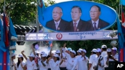 Supporters of Prime Minister Hun Sen's Cambodian People's Party dance under portraits of the party leaders, from left, Chea Sim, Hun Sen and Heng Samrin, during an election campaign in Phnom Penh, Cambodia, Thursday, June 27, 2013. Cambodia's political parties on Thursday kicked off campaigning for the July 28 general election, which is almost certain to see the return to power of Asia's longest-serving leader, Hun Sen.