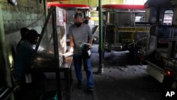 FILE - A man shows his vaccination card before riding a passenger jeep at a terminal in Quezon city, Philippines on Jan. 17, 2022